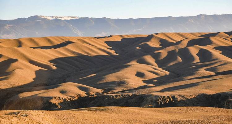 Rollende Sanddünen und trockene Hügel im Altyn-Emel-Park unter sanftem Abendlicht