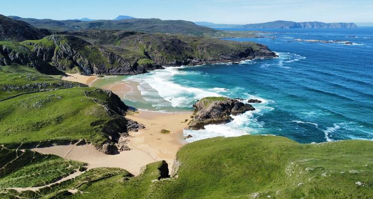 Les falaises verdoyantes isolées et les criques de sable fin avec des vagues turquoise le long de la côte accidentée du Donegal