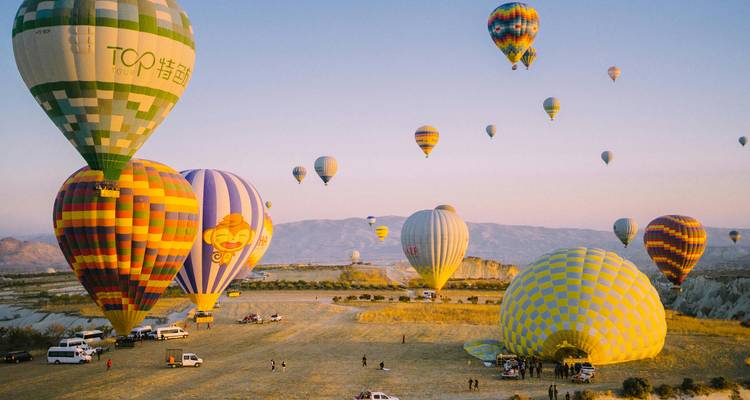 Docenas de coloridos globos aerostáticos preparándose para el despegue al amanecer sobre el valle de Capadocia.