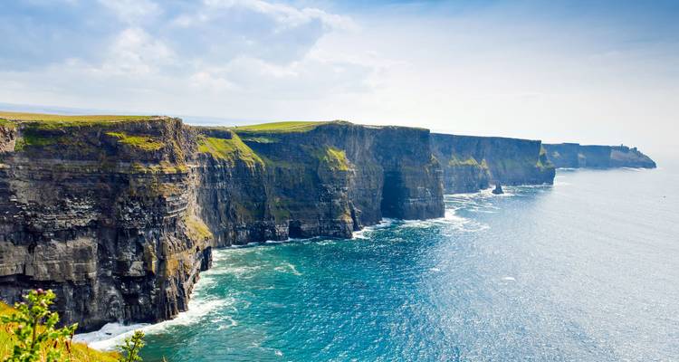 Senkrechte Wände der Cliffs of Moher, die sich an einem hellen Tag über den türkisfarbenen Atlantikgewässern erheben