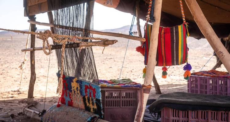 Intérieur de tente nomade avec un métier à tisser en bois et des textiles tissés colorés suspendus dans le désert