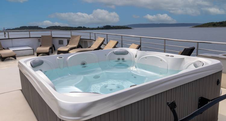 Jacuzzi op het dek gevuld met helder water, omringd door zonnebedden en panoramisch zeezicht.