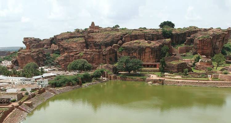Rode zandstenen kliffen en oude structuren die uitkijken over het Agastya-meer in Badami.