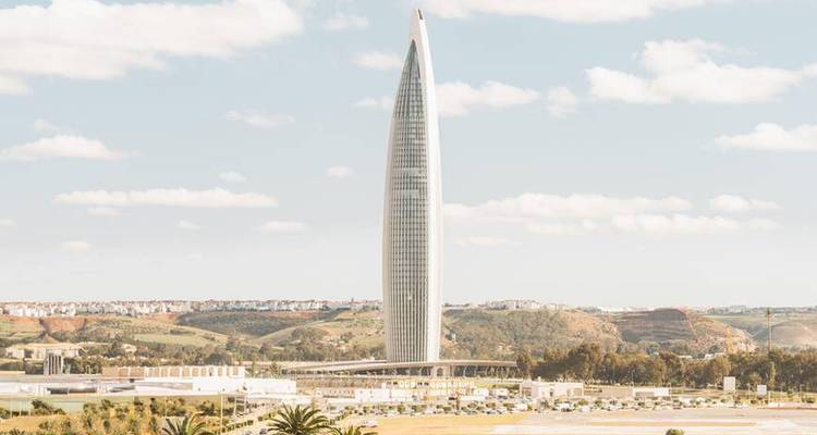 Grand gratte-ciel moderne s'élevant au-dessus des collines ondulantes marocaines à Rabat.