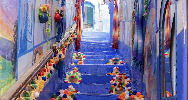 Escalier coloré à Chefchaouen décoré de pompons tricotés et de peintures murales.