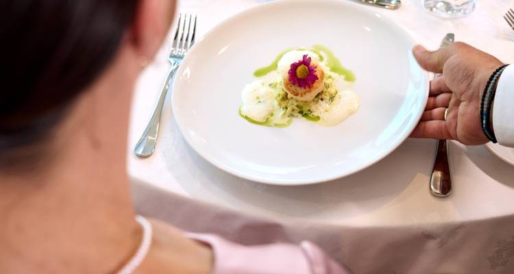 Feinschmecker-Teller mit künstlerischer Anrichtung wird in einem Restaurant mit weißen Tischdecken serviert