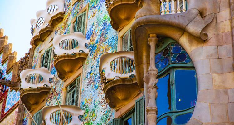 Close-up of Casa Batlló's vibrant mosaic façade and organic balconies in bright sunlight.