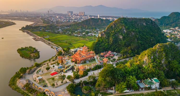 Vista aérea del paisaje urbano de Da Nang, ríos y colinas de piedra caliza verde al atardecer.
