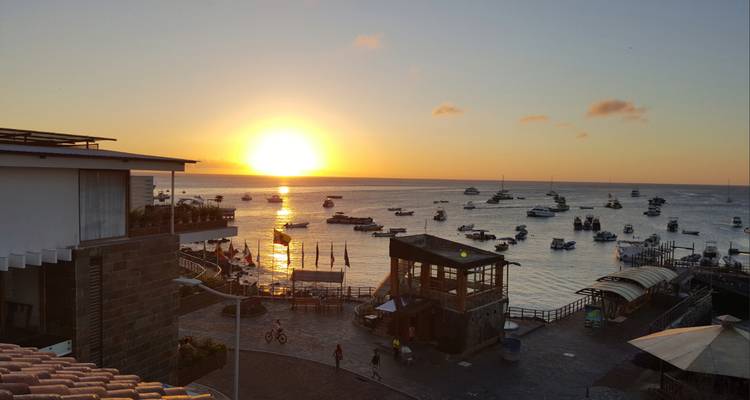 Feuriger Sonnenuntergang über einem Hafen voller vor Anker liegender Boote und Ufergebäude