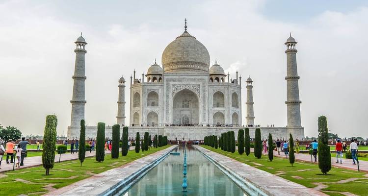 Vista frontal icónica del Taj Mahal con estanque reflectante y visitantes a lo largo del sendero