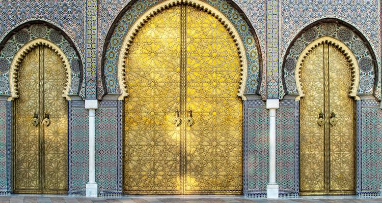 Symmetrical trio of ornate golden doors framed by intricate mosaic tiles at the Royal Palace.