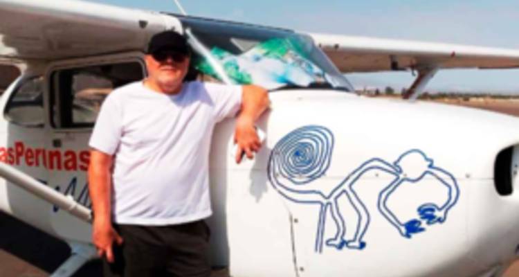 Foto ligeramente borrosa de un hombre apoyado contra una avioneta decorada con un dibujo de las líneas de Nazca en el morro.