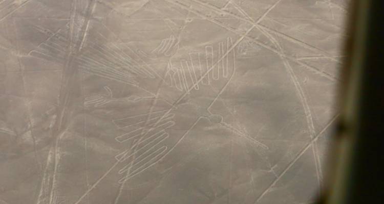 Vista aérea borrosa del gran geoglifo de la línea de Nazca del colibrí en terreno desértico.