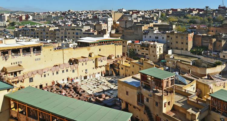 Hoher Aussichtspunkt über die Medina von Fes mit Blick auf Gerbereien, Dächer und entfernte Hügel unter blauem Himmel.