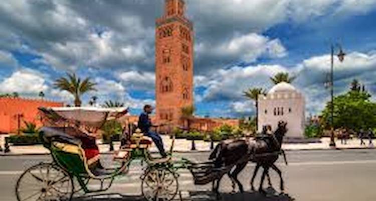 Calèche passant devant un minaret élancé et une rue bordée de palmiers.