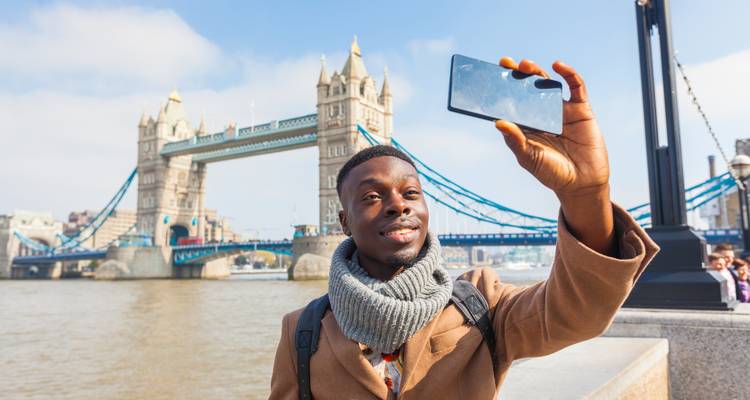 Traveler takes a selfie with the iconic twin towers of Tower Bridge rising over the Thames.