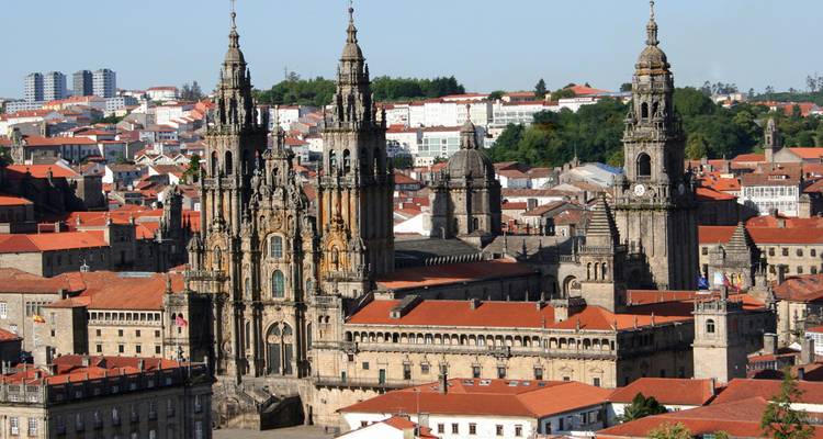Panorama aéreo de la Catedral de Santiago de Compostela elevándose sobre los tejados de tejas rojas.