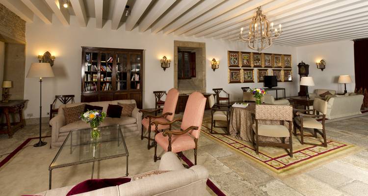 Elegante salón de hotel con sofás de lujo, sillones cómodos, lámparas de araña y arreglos de flores frescas en un edificio histórico de piedra.