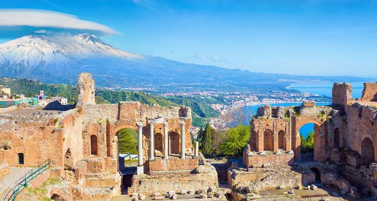 Ruïnes van het oude theater van Taormina met uitzicht op de kustlijn en de met sneeuw bedekte Mount Etna.