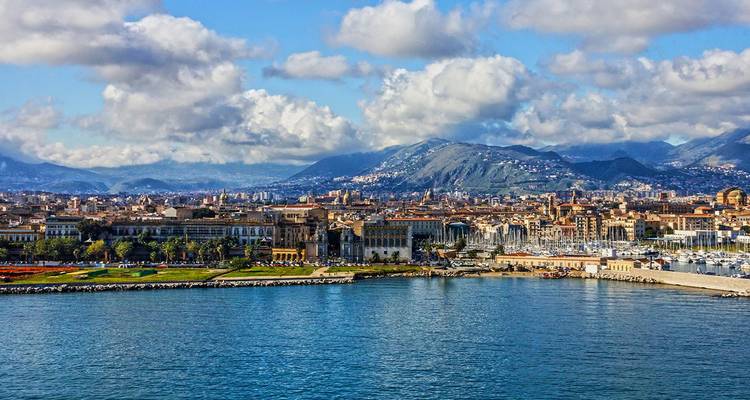 Panoramisch uitzicht op de kust van Palermo met bergen op de achtergrond en jachten in de haven.