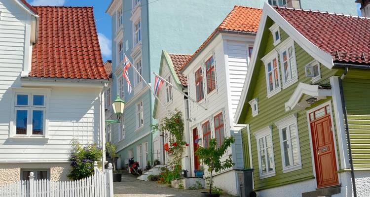 Enge Kopfsteinpflastergasse mit charmanten Holzhäusern in Weiß, Grün und Blau in Bergens Altstadt.