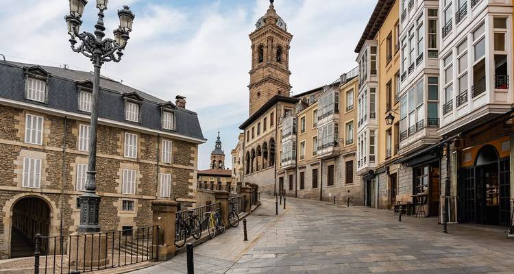 Tranquila calle de piedra bordeada de fachadas históricas y una torre campanario en el casco antiguo de Vitoria-Gasteiz