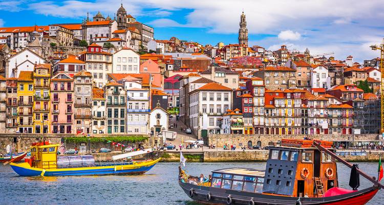 Colorido distrito de Ribeira de Oporto con barcos tradicionales en el río Duero bajo cielos parcialmente nublados