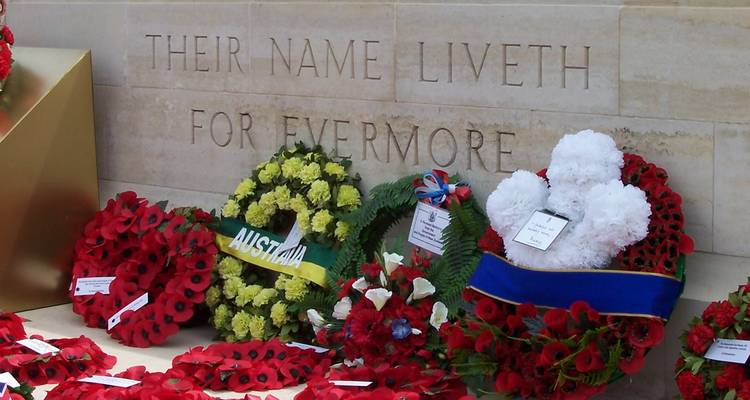 Coronas de amapolas depositadas en un memorial de guerra de piedra grabado con "SU NOMBRE VIVE PARA SIEMPRE".