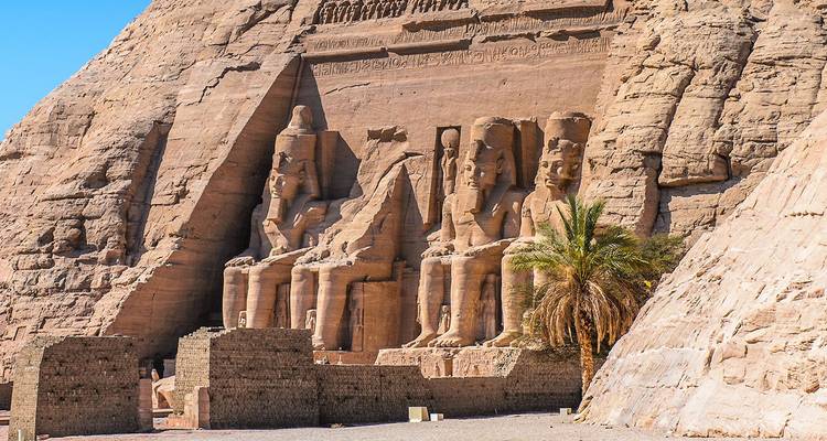 Grand façade of Abu Simbel with four seated pharaoh statues carved into the sandstone cliff.