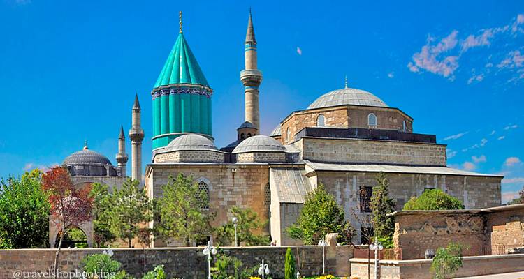 El techo cónico de azulejos turquesas y los minaretes del Museo Mevlana se alzan contra un cielo azul profundo.