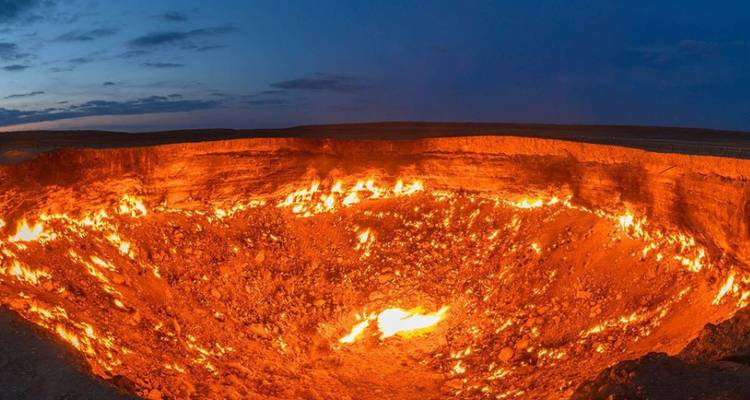 Primer plano panorámico del ardiente cráter de gas de Darvaza ardiendo bajo un cielo crepuscular