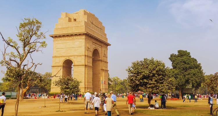Geschäftige Szene am India Gate Denkmal mit Touristen, die spazieren und sich auf den umliegenden Rasenflächen entspannen.
