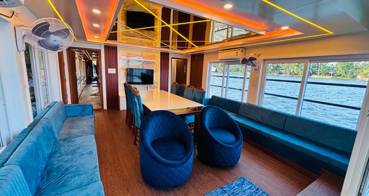 A bright lounge and dining area on a houseboat looks out to the water through large windows.