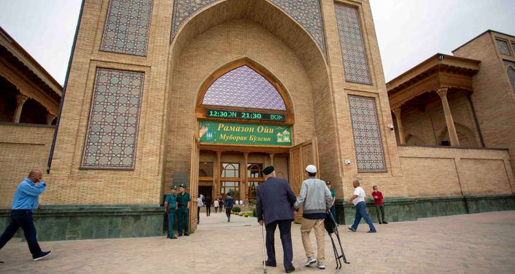 Portail d'entrée avec motifs décoratifs en carrelage et panneau électronique de Ramadan tandis que les visiteurs s'approchent.