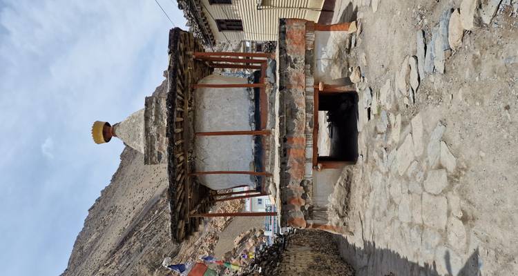 Weathered white chorten on stone platform in arid Himalayan village.
