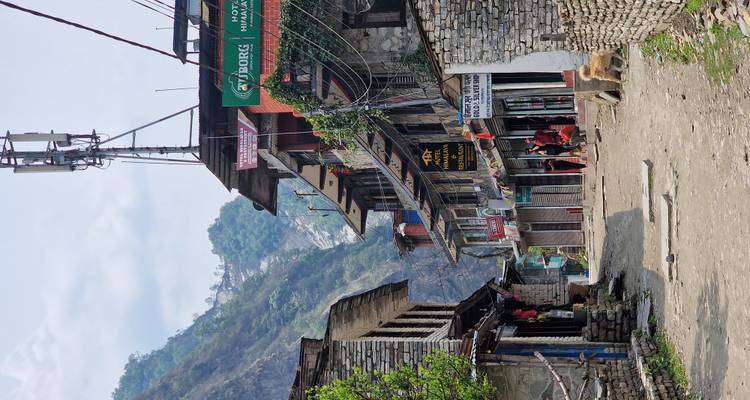 Rustic Himalayan main street lined with lodges, shops and distant cliffs.