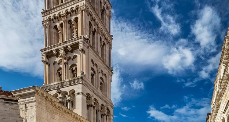 Stenen klokkentoren van de Kathedraal van de Heilige Domnius in Split tegen een levendige blauwe hemel.