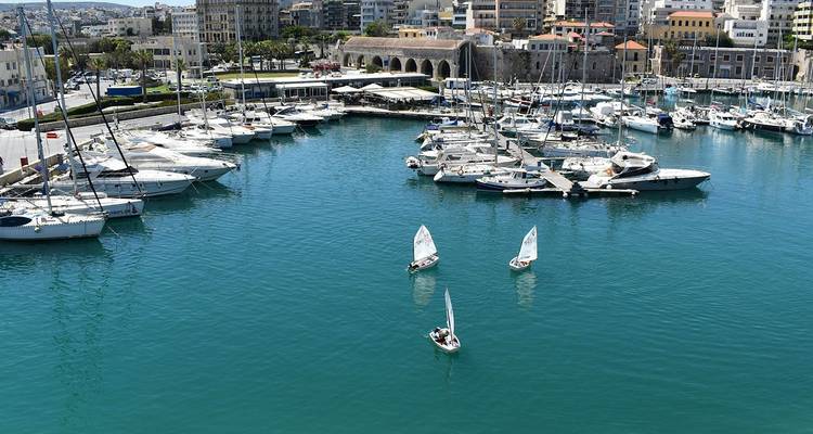 Vista aérea de una marina tranquila llena de yates y pequeños veleros contra agua turquesa.