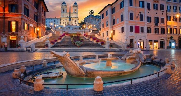 Vue matinale de l'escalier de la Trinité-des-Monts et de la fontaine de la Barcaccia illuminés sous une lumière chaleureuse.