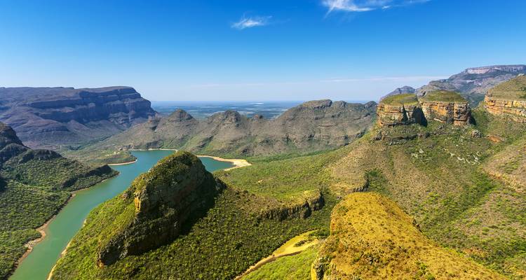 Weids luchtpanorama van ruige kanjoenenwanden, groene valleien en kronkelende riviermeren onder een heldere blauwe hemel