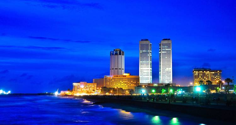 Vista nocturna del moderno skyline de rascacielos de Colombo brillando con luces coloridas a lo largo de la costa.