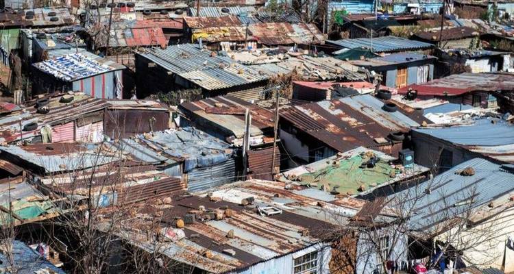 Aerial view of dense, rusted rooftops in an informal settlement.