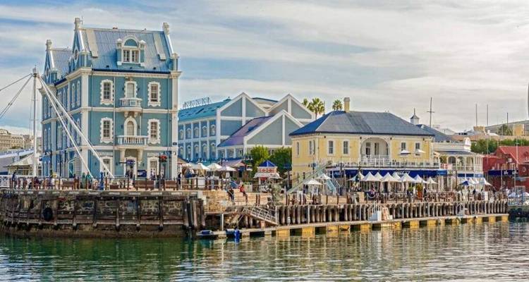 Historic Victorian buildings along Cape Town's V&A Waterfront reflected in the calm basin.