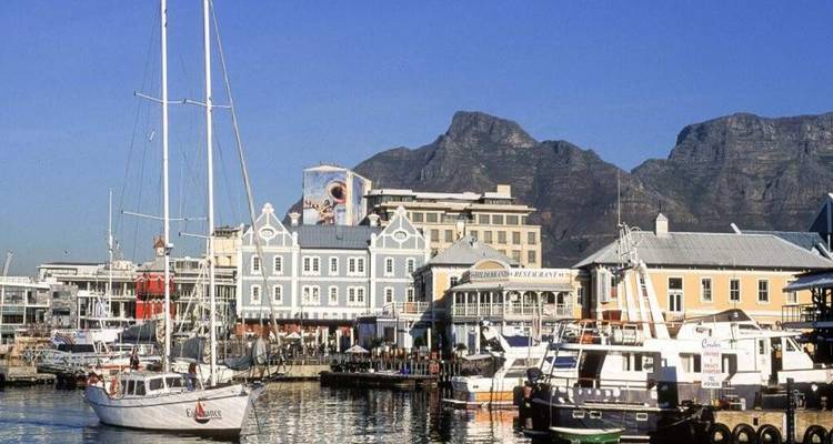 Busy marina at Cape Town’s Waterfront with sailing boats and Table Mountain backdrop under clear skies.