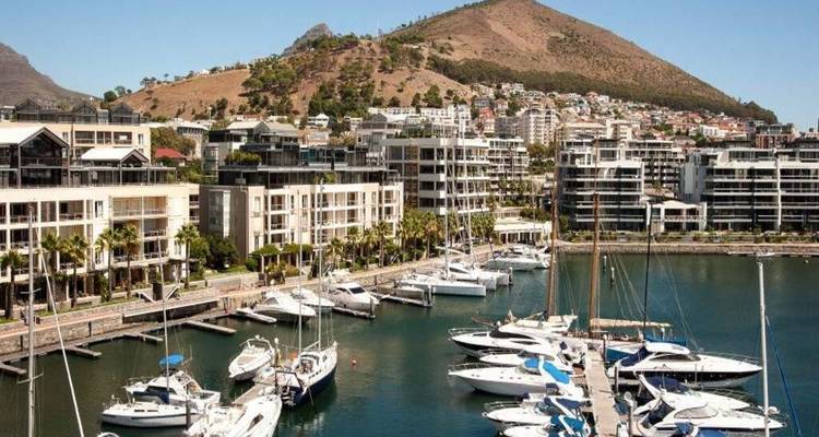 Modern apartment blocks and luxury yachts in Cape Town’s sleek marina with Signal Hill rising behind.