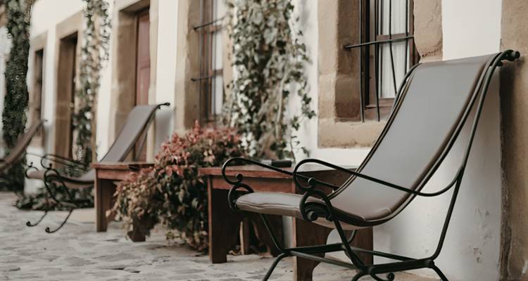 Quiet stone courtyard with wrought-iron lounge chairs beside ivy-covered walls