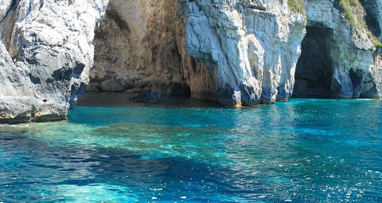 Crystal-clear turquoise sea laps against limestone cliffs and caves