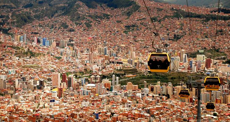 Kabelbanen van La Paz's Mi Teleférico glijden boven het uitgestrekte hooggelegen stadslandschap met bergen op de achtergrond.