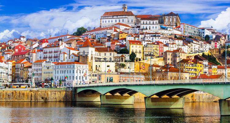 Vue panoramique des bâtiments universitaires historiques de Coimbra perchés sur la colline au-dessus du fleuve Mondego et du pont.