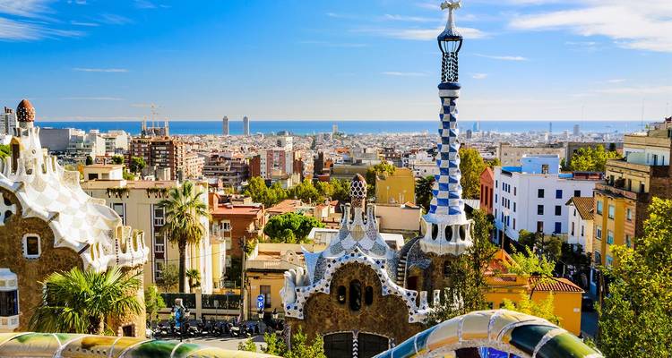Farbenfrohe Mosaikterrassen des Park Güell mit Blick auf die Stadt Barcelona und das Mittelmeer.
